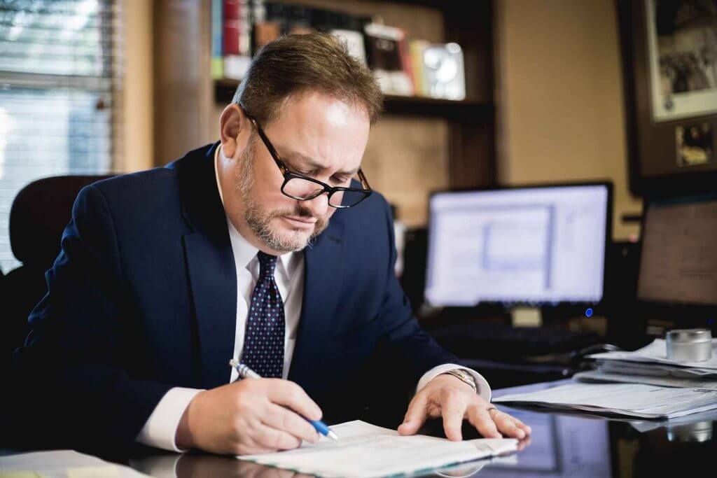 Attorney Dan Soloway in a blue suit reviewing documents in a client's case. 